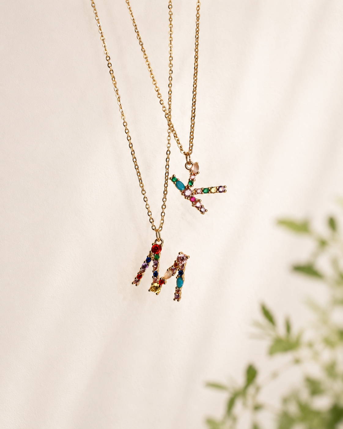 Two gold necklaces with colorful gemstones on a light background