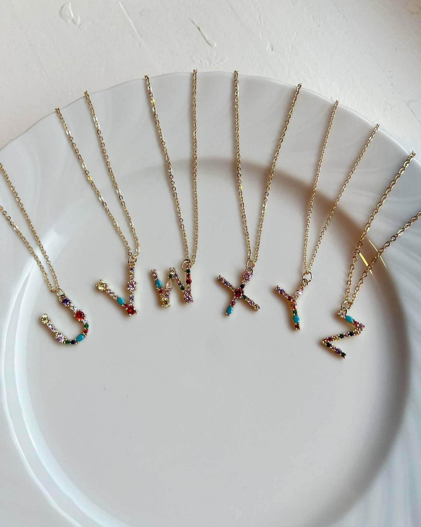 Necklaces with colorful letter pendants on a white plate